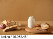 Баночка вкусного соуса Цезарь и багет на бежевом фоне. Стоковое фото, фотограф Pixel_shot / Фотобанк Лори