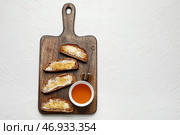 Деревянная доска с вкусными поджаренными хлебцами и медом на белом фоне. Стоковое фото, фотограф Pixel_shot / Фотобанк Лори
