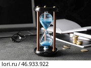 Стильные песочные часы и ноутбук на темном столе в офисе. Концепция дедлайна. Стоковое фото, фотограф Pixel_shot / Фотобанк Лори