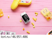 Композиция с пульсоксиметром и таблетками на цветном деревянном фоне. Стоковое фото, фотограф Pixel_shot / Фотобанк Лори