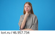 Thoughtful young girl pondering an idea against a bright blue background. Стоковое видео, видеограф Сергей Толмачёв / Фотобанк Лори