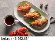 Тарелка с вкусными бутербродами с круассаном и чашкой напитка на сером фоне. Стоковое фото, фотограф Pixel_shot / Фотобанк Лори