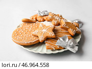 Тарелка с вкусными пряниками и рождественскими бантиками на белом фоне. Стоковое фото, фотограф Pixel_shot / Фотобанк Лори