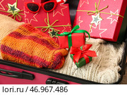 Чемодан с одеждой, подарочными коробками и солнцезащитными очками, крупным планом. Концепция рождественских каникул. Стоковое фото, фотограф Pixel_shot / Фотобанк Лори