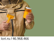 Пчеловод-мужчина в защитном костюме с банкой меда и инструментом на зеленом фоне. Стоковое фото, фотограф Pixel_shot / Фотобанк Лори