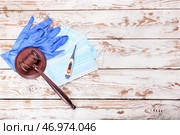 Молоток судьи, перчатки, маски и термометр на деревянном фоне. Концепция реформы здравоохранения. Стоковое фото, фотограф Pixel_shot / Фотобанк Лори