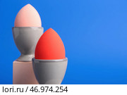 Креативная композиция с держателями для яиц и губками для макияжа на цветном фоне. Стоковое фото, фотограф Pixel_shot / Фотобанк Лори