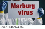 Doctor holding a banner with text Marburg Virus sign. Scientist in protective gear, gloves and medical mask. New epidemic illness. Outbreak of infectious disease spreading, worldwide pandemic. Стоковое AI-видео, аниматор Марина Демидюк / Фотобанк Лори