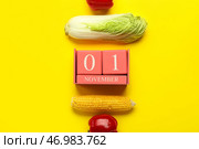 Китайская капуста, сладкий перец, кукурузный початок и кубический календарь с датой 1 НОЯБРЯ на желтом фоне. Концепция Всемирного дня вегана. Стоковое фото, фотограф Pixel_shot / Фотобанк Лори