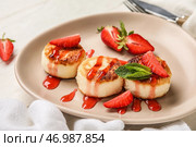 Тарелка с вкусными сырниками, покрытыми соусом и ягодами на белом деревянном столе. Стоковое фото, фотограф Pixel_shot / Фотобанк Лори