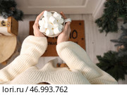 Женщина, держащая чашку какао с маршмеллоу у двери дома на канун Рождества, вид сверху. Стоковое фото, фотограф Pixel_shot / Фотобанк Лори