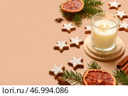 Звездообразные имбирные пряники с корицей, сушеным апельсином, ветками пихты и горящей свечой на коричневом фоне. Стоковое фото, фотограф Pixel_shot / Фотобанк Лори