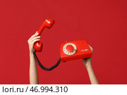 Женские руки, держащие старый телефон на красном фоне. Празднование Дня святого Валентина. Стоковое фото, фотограф Pixel_shot / Фотобанк Лори