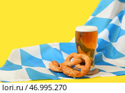 Стакан с холодным пивом, флаг Баварии и вкусные брецели на желтом фоне. Празднование Октоберфеста. Стоковое фото, фотограф Pixel_shot / Фотобанк Лори