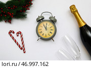 Будильник с ветками новогодней ели и бутылкой шампанского на белом фоне. Стоковое фото, фотограф Pixel_shot / Фотобанк Лори