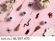 Хэллоуинская композиция с конфетными насекомыми, скелетом и метлами на розовом фоне. Стоковое фото, фотограф Pixel_shot / Фотобанк Лори