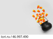 Композиция к Хэллоуину с опрокинутым котлом и карамельным кукурузным початком на сером фоне. Стоковое фото, фотограф Pixel_shot / Фотобанк Лори