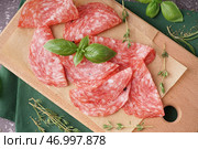 Деревянная доска с ломтями вкусного салями на столе. Стоковое фото, фотограф Pixel_shot / Фотобанк Лори