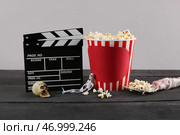 Ведро с попкорном, хэллоуинскими украшениями и кинематографическим щитом на деревянном столе на сером фоне. Стоковое фото, фотограф Pixel_shot / Фотобанк Лори