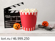 Ведро с попкорном с украшениями к Хэллоуину и кинематографическим щитом на деревянном столе на фоне белого фона. Стоковое фото, фотограф Pixel_shot / Фотобанк Лори