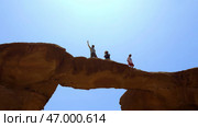 Adventurous people enjoy a remarkable rock arch under a clear blue sky on a glorious day. Стоковое фото, фотограф David Kashakhi / Фотобанк Лори