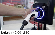 Hand plugging in an electric vehicle charger station for seamless energy replenishment. Стоковое фото, фотограф David Kashakhi / Фотобанк Лори