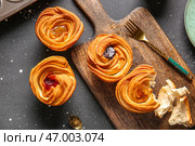 Деревянная доска с вкусными круффинами с шоколадом и вареньем на черном фоне. Стоковое фото, фотограф Pixel_shot / Фотобанк Лори