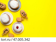 Композиция Хануки с крутящимися вертящимися драйделями и пончиками на жёлтом фоне. Стоковое фото, фотограф Pixel_shot / Фотобанк Лори