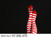 Молодая женщина в рождественских чулках с мячом на темном фоне. Стоковое фото, фотограф Pixel_shot / Фотобанк Лори