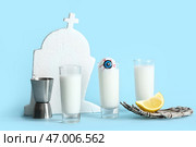 Снимки вкусного белого коктейля, мерного стакана и скелетной руки для Хэллоуина на голубом фоне. Стоковое фото, фотограф Pixel_shot / Фотобанк Лори