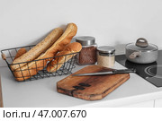 Белый кухонный стол с разделочной доской, багетами в корзине и ножом. Стоковое фото, фотограф Pixel_shot / Фотобанк Лори