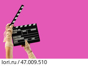 Руки мумии с кинематографическим хлопушкой на розовом фоне. Празднование Хэллоуина. Стоковое фото, фотограф Pixel_shot / Фотобанк Лори