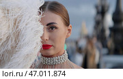 A young model with vulgar makeup standing on the street with feathers. Стоковое фото, фотограф David Kashakhi / Фотобанк Лори
