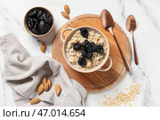 Горшочек вкусной овсянки с черносливом, молоком, миндалем и ложки на мраморном фоне. Стоковое фото, фотограф Pixel_shot / Фотобанк Лори