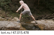 Legs of a boy jumping trough a creek in slow motion. Стоковое фото, фотограф David Kashakhi / Фотобанк Лори