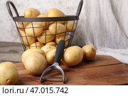Доска и корзина с сырыми картофелинами на деревянном столе, крупным планом. Стоковое фото, фотограф Pixel_shot / Фотобанк Лори