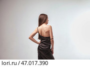 Elegant Indoor Portrait of a Woman in a Black Dress Against a Minimalist Background. Стоковое фото, фотограф Aleksandr Golubev / Фотобанк Лори