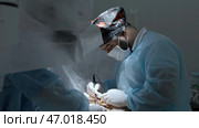 Team of doctors and surgeons processing surgical operation in operating room. Стоковое фото, фотограф David Kashakhi / Фотобанк Лори