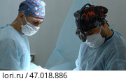 Close up shot of doctor in surgical loupe, sterile mask and protective hair cover looking at the camera. Стоковое фото, фотограф David Kashakhi / Фотобанк Лори
