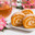 Delicate pumpkin and carrot roll with cream filling, pink alstroemeria and tea on a white background close up. Стоковое фото, фотограф Неведицына Елена / Фотобанк Лори