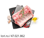 Грифельная тарелка с сырыми свиными ребрышками и специями на белом фоне. Стоковое фото, фотограф Pixel_shot / Фотобанк Лори