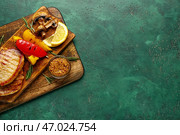 Доска с вкусными жареными перцами, грибами и стейками на цветном фоне. Стоковое фото, фотограф Pixel_shot / Фотобанк Лори