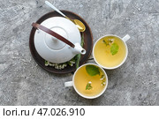Чайник и чашки с травяным чаем на сером фоне. Стоковое фото, фотограф Pixel_shot / Фотобанк Лори