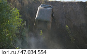 Dramatic view of an off-road vehicle climbing a steep cliff. The vehicle is tilted at a dangerous angle. Extreme off-road racing. Стоковое фото, фотограф Воловодов Владимир / Фотобанк Лори
