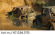 Two SUVs are standing in a muddy ditch. In front of them is a steep dirt wall. Extreme racing on off-road vehicles. Стоковое фото, фотограф Воловодов Владимир / Фотобанк Лори