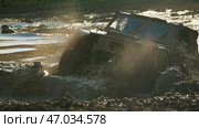 Dirty powerful SUV stuck in a muddy puddle, spraying water and mud high into the air. Epic moment of extreme off-road competitions. Стоковое фото, фотограф Воловодов Владимир / Фотобанк Лори