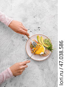 Женщина ест вкусный бутерброд с флорентийским яйцом, беконом и авокадо на светлом фоне. Стоковое фото, фотограф Pixel_shot / Фотобанк Лори