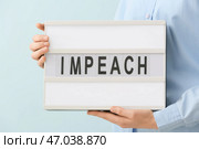 Женщина держит доску с текстом IMPEACH на цветном фоне. Стоковое фото, фотограф Pixel_shot / Фотобанк Лори