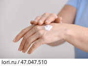 Зрелая женщина, применяя крем для рук на сером фоне, близком расстоянии. Стоковое фото, фотограф Pixel_shot / Фотобанк Лори