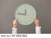 Человек, держащий часы на сером фоне. Концепция тайм-менеджмента. Стоковое фото, фотограф Pixel_shot / Фотобанк Лори